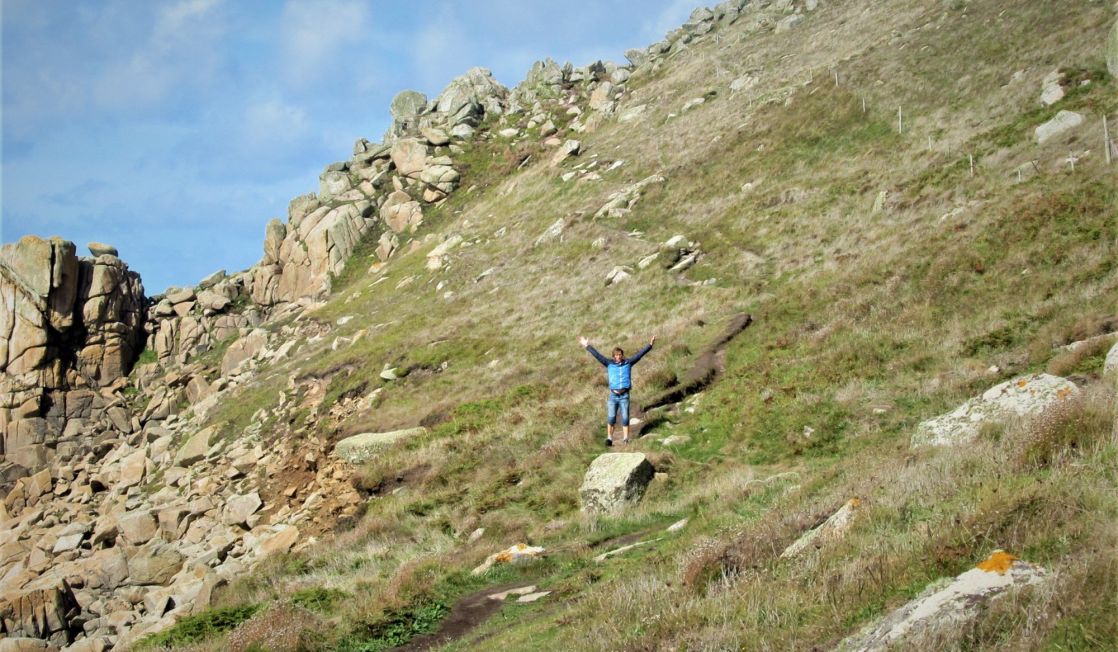 Walker waving on the coast path